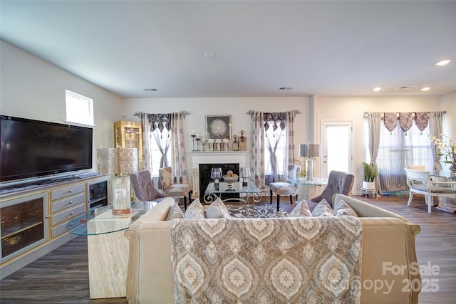 living room featuring dark wood-type flooring, recessed lighting, a fireplace, and visible vents