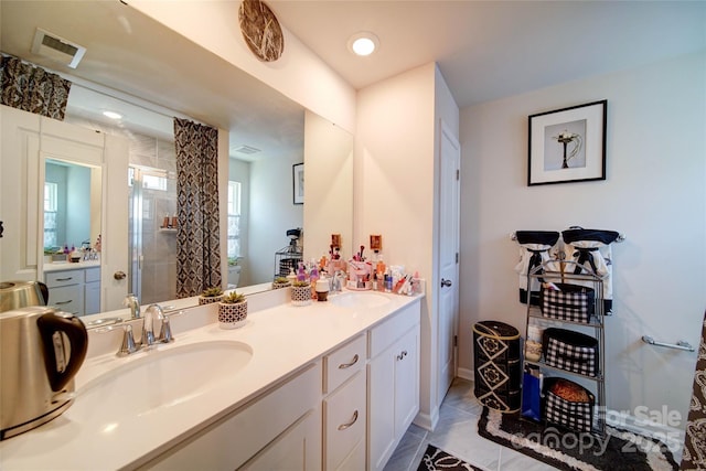full bathroom featuring double vanity, visible vents, a stall shower, and a sink
