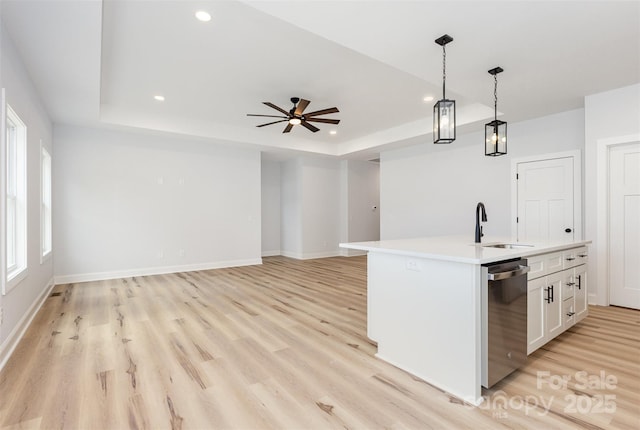 kitchen featuring a raised ceiling, dishwasher, a sink, recessed lighting, and pendant lighting