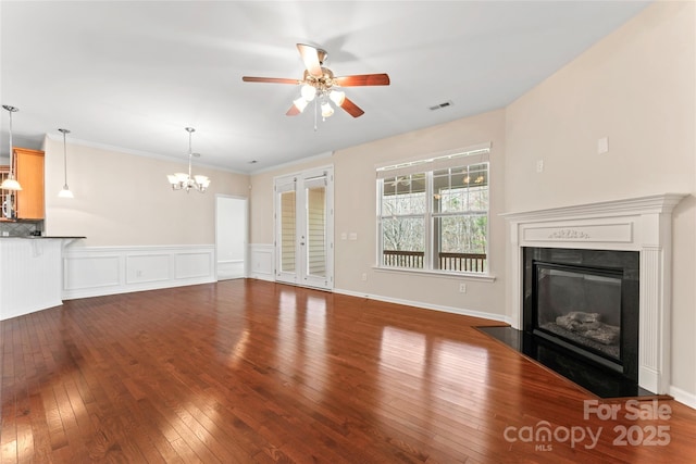 3104 Streamhaven Dr, Indian Land, SC 29707 - unfurnished living room with visible vents, hardwood / wood-style flooring, wainscoting, a glass covered fireplace, and ceiling fan with notable chandelier