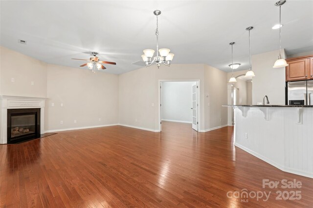 3104 Streamhaven Dr, Indian Land, SC 29707 - unfurnished living room with visible vents, a fireplace with flush hearth, ceiling fan with notable chandelier, a sink, and wood finished floors