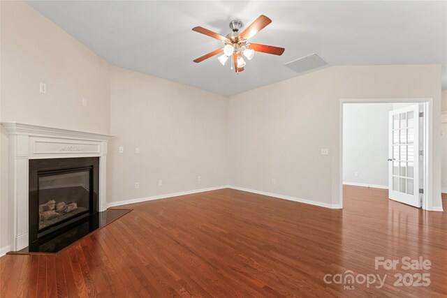 3104 Streamhaven Dr, Indian Land, SC 29707 - unfurnished living room featuring baseboards, ceiling fan, vaulted ceiling, wood finished floors, and a glass covered fireplace