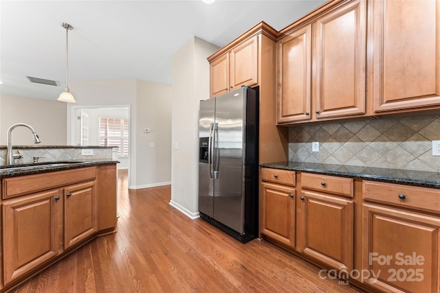 3104 Streamhaven Dr, Indian Land, SC 29707 - kitchen with dark stone countertops, wood finished floors, visible vents, a sink, and stainless steel refrigerator with ice dispenser