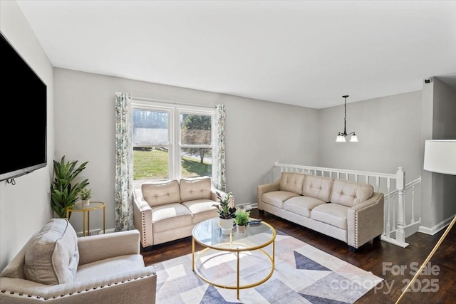 living room with baseboards, an inviting chandelier, and wood finished floors