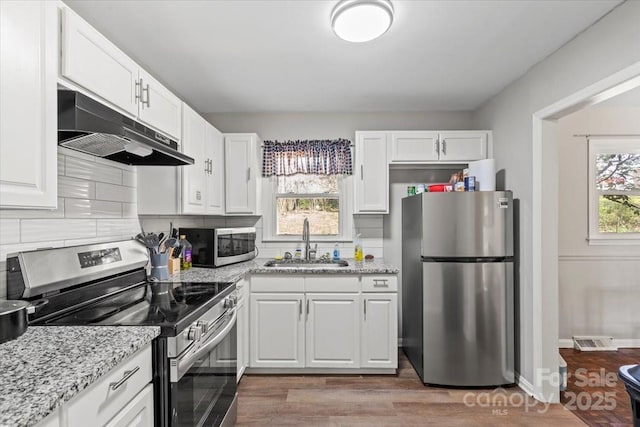 kitchen featuring visible vents, under cabinet range hood, a sink, plenty of natural light, and appliances with stainless steel finishes