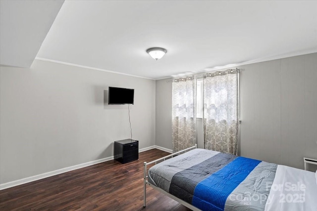 bedroom with crown molding, wood finished floors, and baseboards