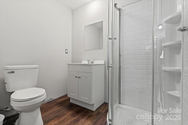 full bathroom with a stall shower, toilet, vanity, and wood finished floors