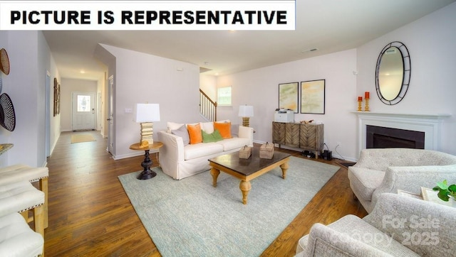 living room featuring a healthy amount of sunlight, a fireplace, stairs, and wood finished floors