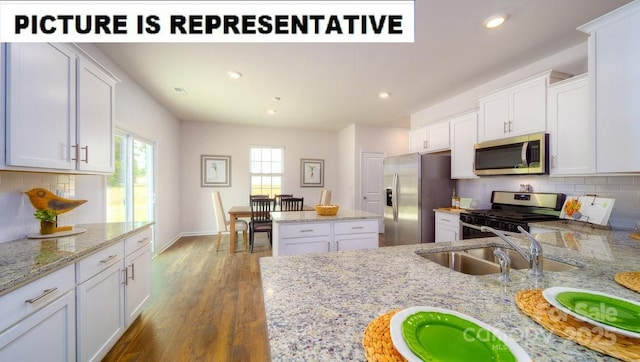 kitchen with wood finished floors, recessed lighting, a sink, appliances with stainless steel finishes, and white cabinetry