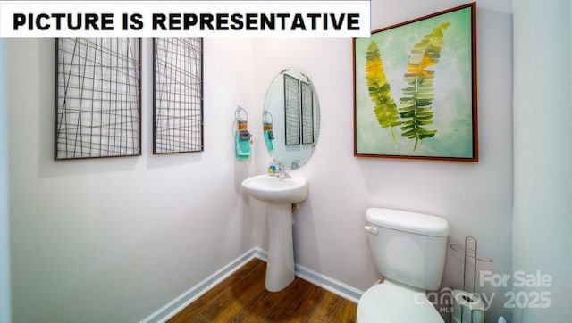 half bath with baseboards, toilet, and wood finished floors