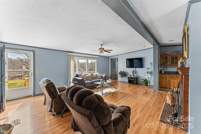 living room with visible vents, a textured ceiling, ceiling fan, and light wood finished floors