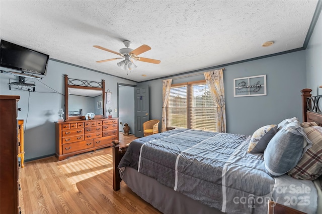 bedroom featuring ceiling fan, a textured ceiling, wood finished floors, and ornamental molding