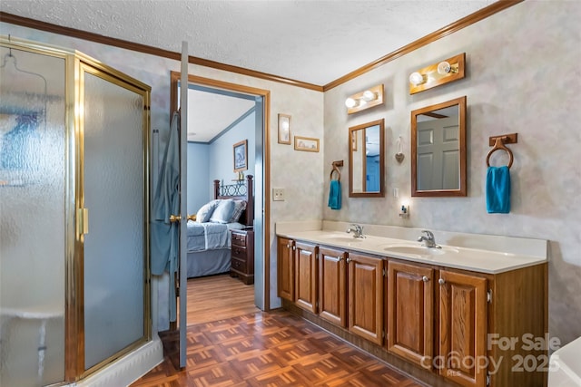 ensuite bathroom featuring a sink, ornamental molding, a stall shower, and a textured ceiling