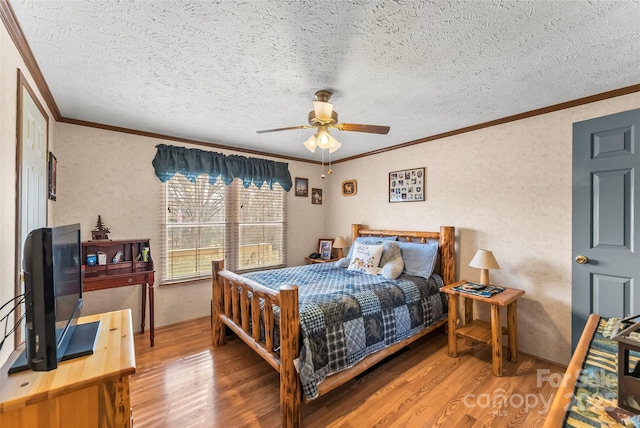 bedroom with ornamental molding, a textured ceiling, a ceiling fan, and wood finished floors