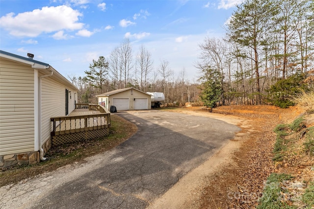 view of yard with a deck, a detached garage, and an outbuilding