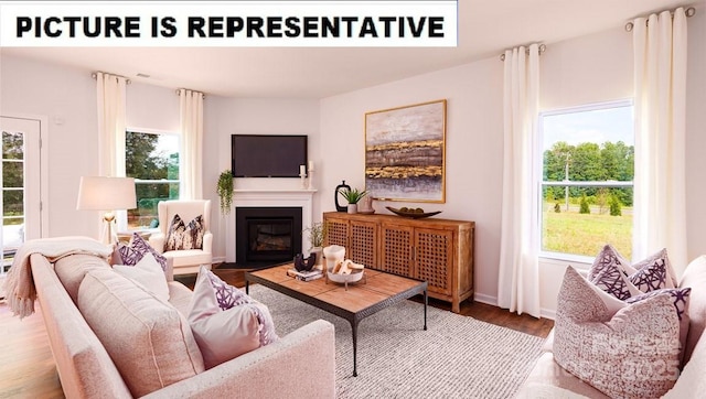 living area featuring baseboards, a fireplace with flush hearth, and wood finished floors