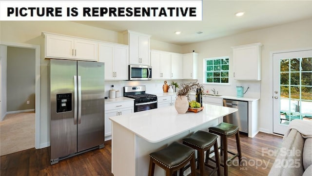 kitchen with stainless steel appliances, a kitchen breakfast bar, white cabinets, and light countertops