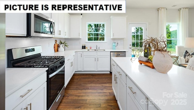 kitchen with a sink, dark wood-style floors, white cabinetry, stainless steel appliances, and light countertops