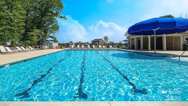 community pool with a patio area and fence