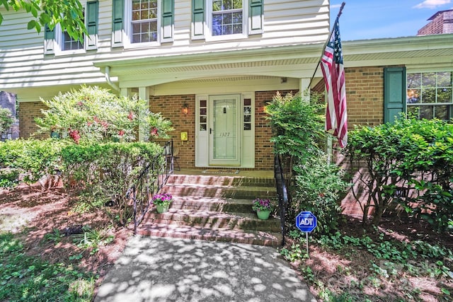 view of exterior entry with covered porch and brick siding
