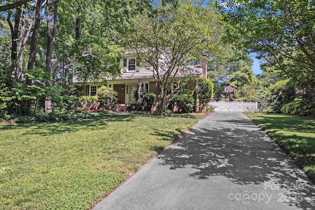 obstructed view of property featuring fence, driveway, a gate, and a front yard
