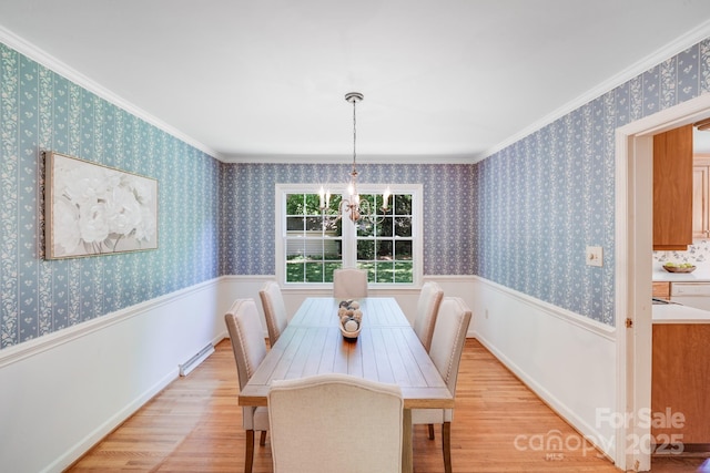 dining room with wainscoting, ornamental molding, a baseboard heating unit, and light wood-type flooring