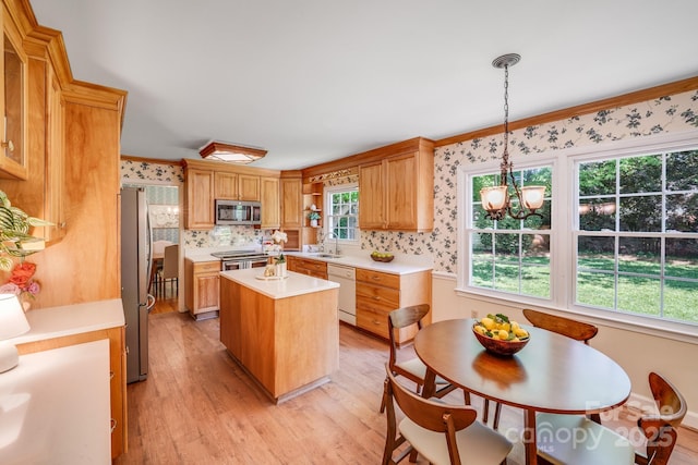 kitchen with a kitchen island, light wood-type flooring, light countertops, a sink, and appliances with stainless steel finishes