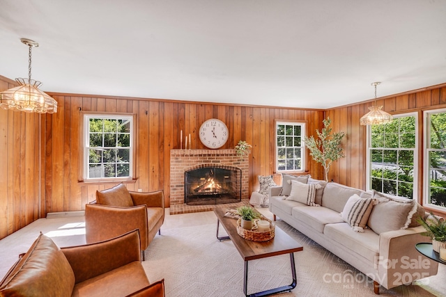 living room featuring a brick fireplace, a chandelier, and wooden walls