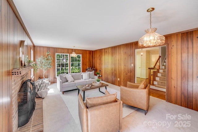 living room with stairway, a brick fireplace, wood walls, and light colored carpet