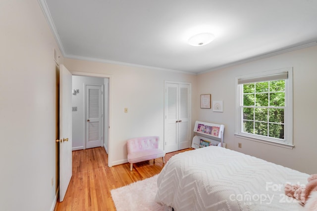 bedroom with a closet, ornamental molding, light wood finished floors, and baseboards
