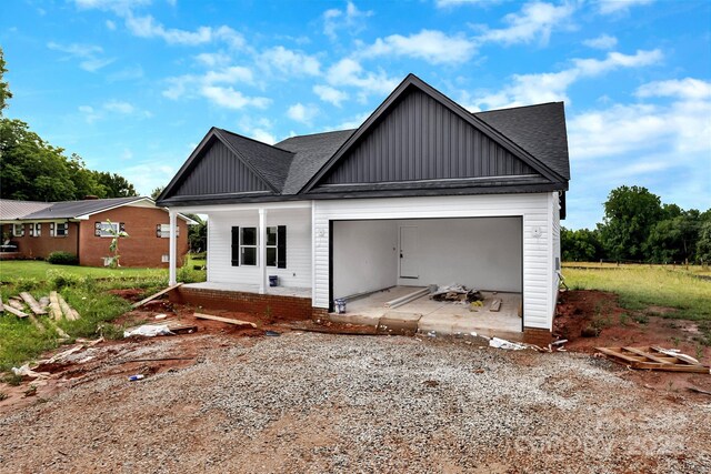 8455 W NC-152 Hwy, Mooresville, NC 28115 - rear view of house featuring board and batten siding, roof with shingles, a garage, a porch, and driveway