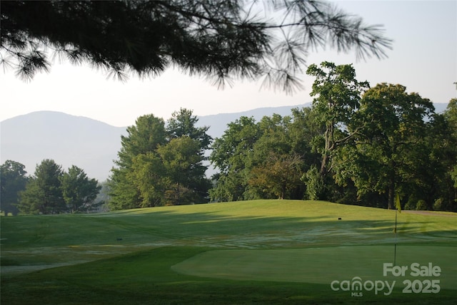 view of property's community with a yard, a mountain view, and golf course view
