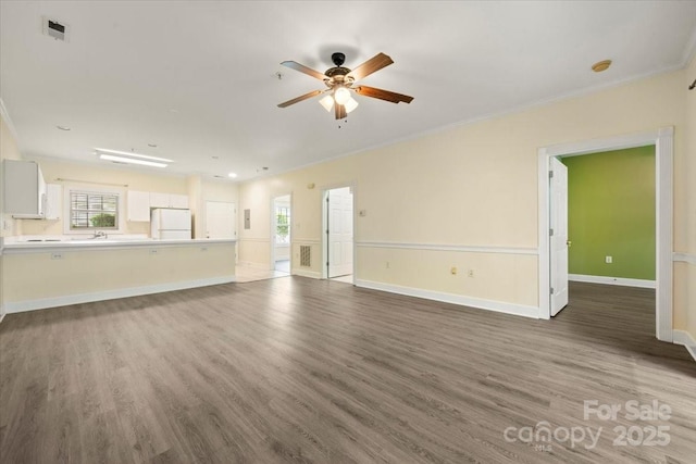 unfurnished living room featuring wood finished floors, visible vents, crown molding, ceiling fan, and baseboards