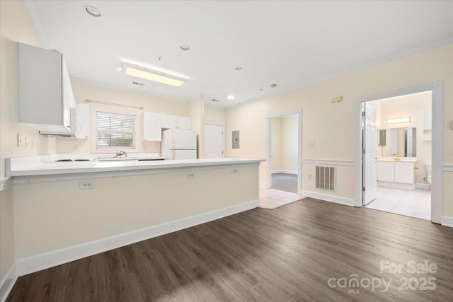 kitchen with freestanding refrigerator, visible vents, a peninsula, wood finished floors, and light countertops
