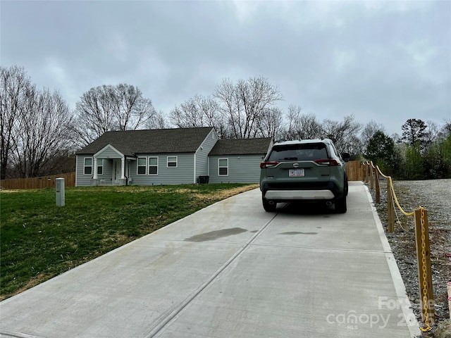 single story home with a front lawn, fence, driveway, and a shingled roof