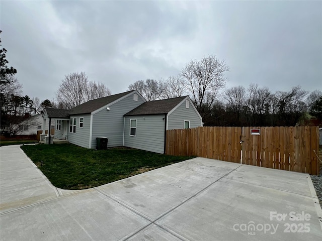 view of home's exterior featuring a lawn, roof with shingles, and fence