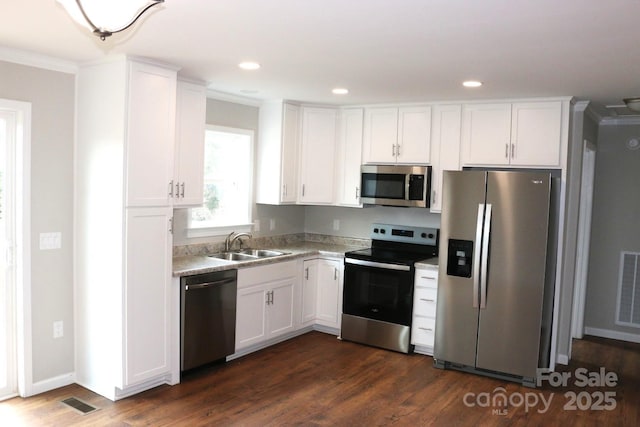 kitchen with dark wood-style flooring, a sink, stainless steel appliances, light countertops, and white cabinetry