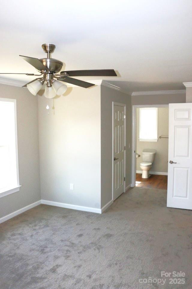 carpeted empty room featuring baseboards, ceiling fan, and crown molding