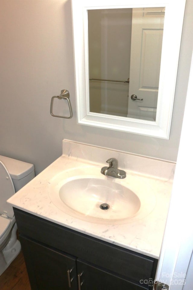 bathroom featuring toilet, wood finished floors, and vanity