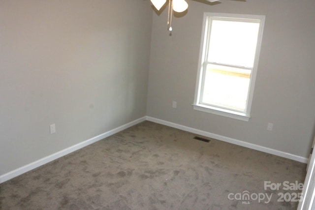 carpeted empty room featuring visible vents, baseboards, and ceiling fan