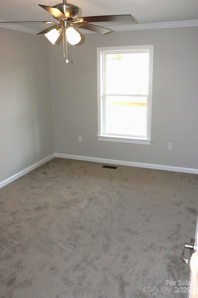 unfurnished room featuring carpet, baseboards, a ceiling fan, visible vents, and ornamental molding