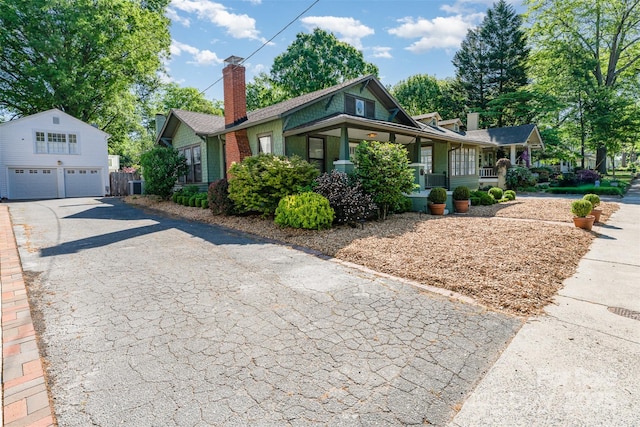 view of front of house with covered porch, a chimney, a garage, central AC, and an outdoor structure