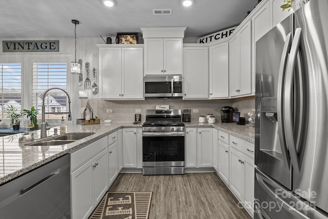 7172 Indigo Way, Denver, NC 28037 - kitchen featuring appliances with stainless steel finishes, a sink, white cabinetry, decorative backsplash, and recessed lighting