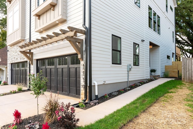 view of side of home with an attached garage, fence, and driveway