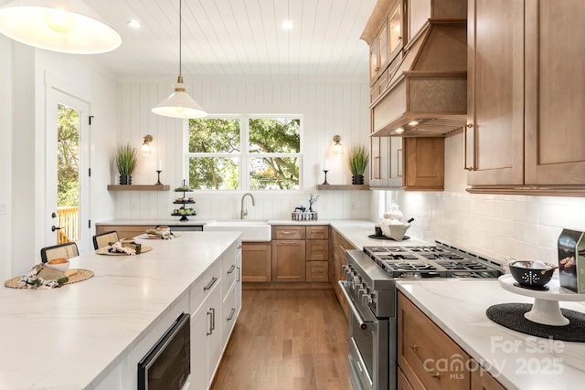 kitchen featuring open shelves, a sink, high end stove, custom range hood, and tasteful backsplash