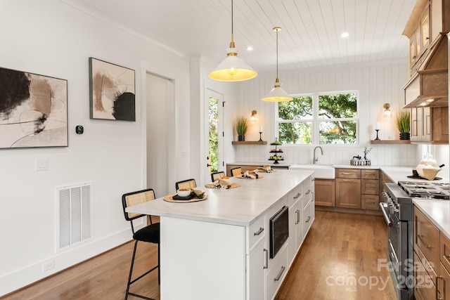 kitchen with visible vents, stainless steel range, a sink, a kitchen island, and built in microwave
