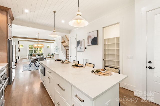 kitchen featuring hanging light fixtures, beamed ceiling, dark wood-style floors, and a center island