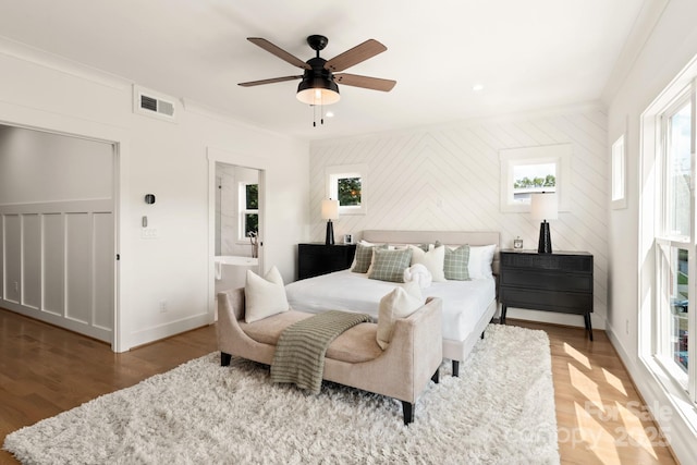 bedroom featuring wood finished floors, visible vents, baseboards, ceiling fan, and ornamental molding