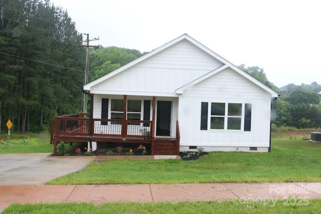 view of front of house with board and batten siding, a front yard, covered porch, and crawl space