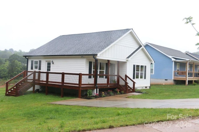 view of front facade with a front yard, crawl space, roof with shingles, and a wooden deck